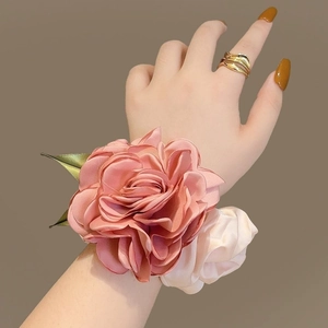 Gros plan d'un chouchou rose en satin rose et crème avec des feuilles vertes