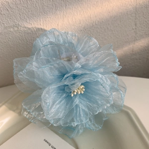 Détail d'une pince à cheveux fleur en organza bleu clair avec finition nacrée élégante