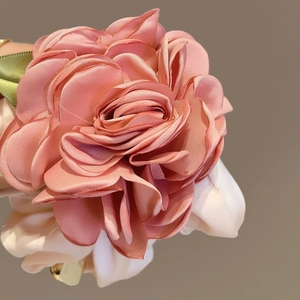Détail macro des pétales de fleurs en satin rose et feuilles en soie sur le chouchou