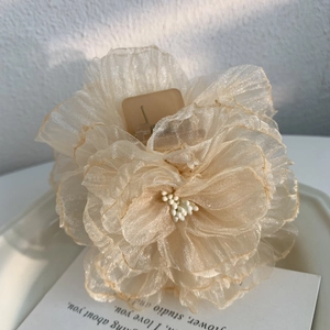 Détail de la pince à cheveux fleur en organza champagne avec centre de perles blanches