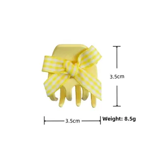 Detail showing a 3.5cm mini resin hair claw with a yellow floral checkered bow