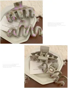 Detailed close-up of two acetate hair claws with marble patterns on a wooden tray