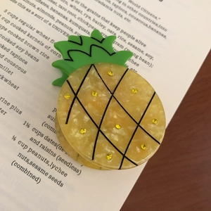 Detailed view of acetate pineapple hair claw clip with yellow rhinestones and green leaves