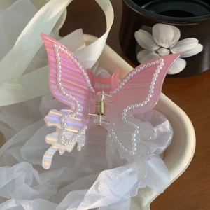 Détail d'une pince à cheveux papillon rose nacré avec des perles délicates sur les bords