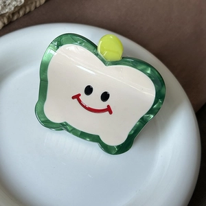 Detailed view of an acetate apple hair claw clip featuring a cute smiling face design