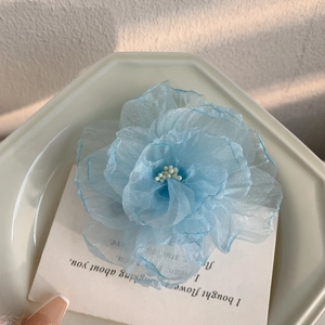 Détail de la pince à cheveux fleur en organza bleu clair avec centre en perles