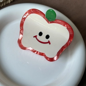 Detail view of apple-shaped acetate hair claw clip with a cute smiley face and leaf