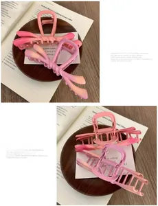 Macro detail of large gradient purple and pink bow hair claw clips on a wooden tray