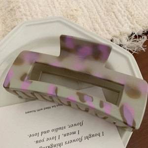 Detail of a large square hair claw clip with purple leopard print on a ceramic plate