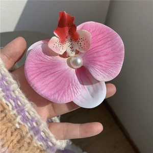 Gros plan détaillé d'une pince à cheveux orchidée rose avec pétales et perle centrale