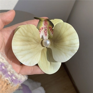 Vue détaillée d'une pince à cheveux orchidée jaune avec pétales réalistes et perle centrale