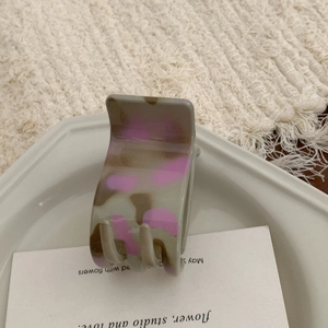 Close-up of a matte grey and pink spotted hair claw clip on an aesthetic tray