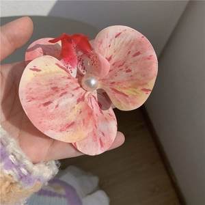 Détail de la pince à cheveux orchidée avec pétales roses tachetés et perle centrale