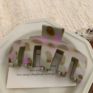 Detailed view of large grey and pink patterned hair claw clip on white ceramic tray