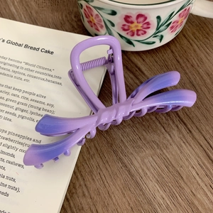 Macro shot of gradient purple bow hair claw clip with a matte finish on vintage books