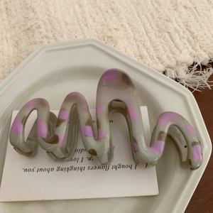 Detail shot of wavy gray and purple speckled resin hair claw clip on a ceramic tray