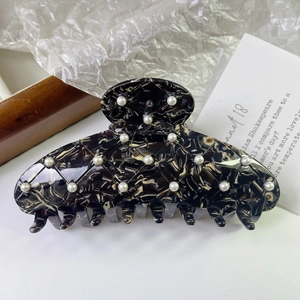Détail d'une grande pince à cheveux en acétate avec motif matelassé et perles