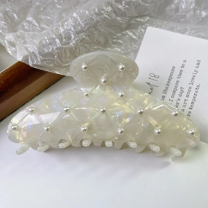 Détail d'une pince à cheveux en acétate crème avec texture matelassée et perles