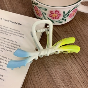 Detail of gradient blue and yellow butterfly hair claw clip on wooden table
