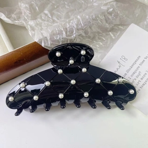 Détail d'une pince à cheveux noire brillante à motif matelassé et perles nacrées