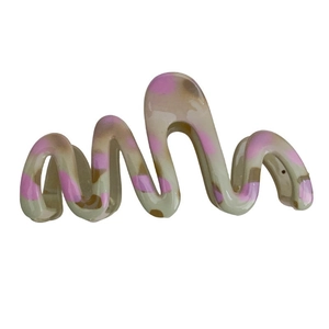Large pink and beige wavy resin hair claw clip with abstract spotted texture on white background