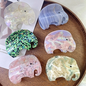 Pinces à cheveux éléphant en acétate de six couleurs sur un plateau en bois