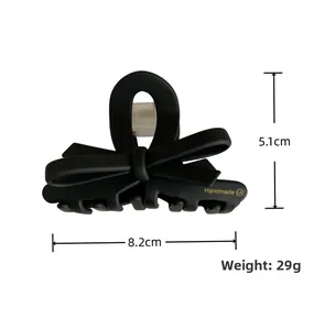 Dettaglio della pinza per capelli a fiocco nero opaco con scritte dorate, larghezza 8.2cm