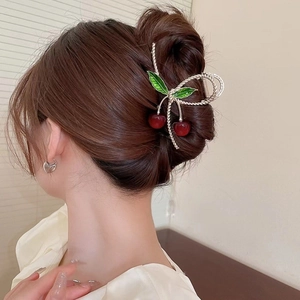 Rear view of a model wearing a silver metal cherry hair claw with red beads and green leaves