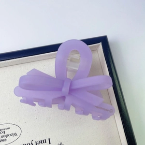 Dettaglio di un mollettone a fiocco viola opaco con scritte fatte a mano incise
