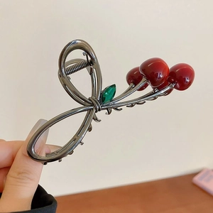 Detail of a gunmetal shark hair claw clip featuring red cherries and green leaves