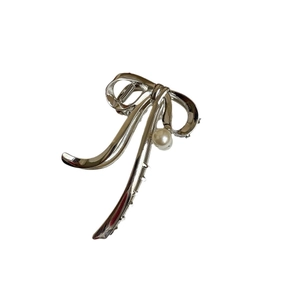 Elegante pinza per capelli a fiocco in metallo argento con perla su sfondo bianco neutro