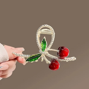 Detailed macro view of the cherry hair claw clip showing red enamel and gold alloy finish