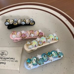 Sparkling rhinestone hair clips in four colors set on a decorative vintage ceramic plate
