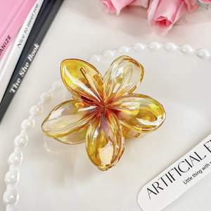 Detailed view of amber yellow translucent plumeria hair claw clip with aurora coating