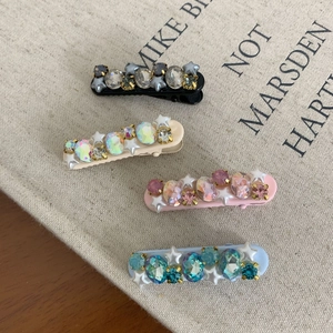 Set of four stylish rhinestone hair clips with star accents in black, cream, pink, and blue