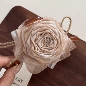 Detail of fabric rose hair claw clip with dried rose petals and jute rope accents