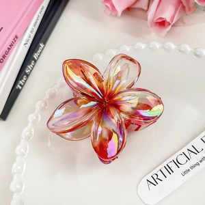 Close-up of translucent gradient plumeria hair claw clip on a decorative white plate