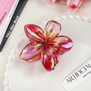 Close-up of iridescent gradient pink flower hair claw clip on a pearl jewelry tray