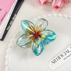 Detail of colorful gradient plumeria hair claw clip with iridescent finish on white ceramic plate