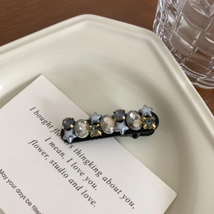 Detail of luxury rhinestone hair clip with grey crystals and star on white ceramic plate
