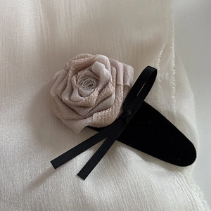 Detail shot of a handmade champagne fabric rose hair claw with elegant black ribbon bow
