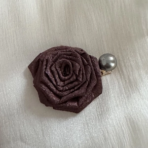 Detail of a large rose-shaped hair claw clip with vintage texture and grey pearl accent