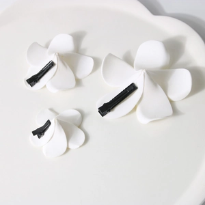 Détail de pinces à cheveux frangipanier blanches en trois tailles sur une assiette en céramique