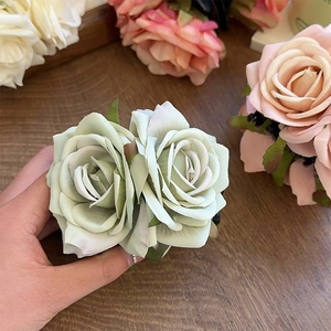 Détail de la pince à cheveux rose en soie vert clair avec feuilles sur une table en bois