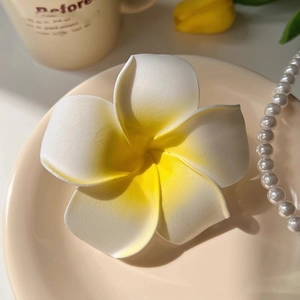 Détail d'une pince à cheveux fleur de frangipanier réaliste avec dégradé jaune