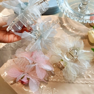 Détail de grandes pinces à cheveux fleur en organza bleu rose et crème sur plateau