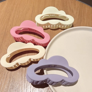 Matte cloud hair claws in pastel colors displayed on a wooden surface and ceramic plate