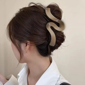 Macro detail of large wave hair claw clip in matte light brown on a female model