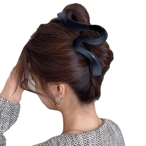 Detailed view of a large black wavy claw clip securing a hair bun on a female model