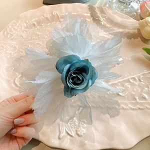 Gros plan d'une pince à cheveux rose bleue avec des pétales en tissu blanc léger